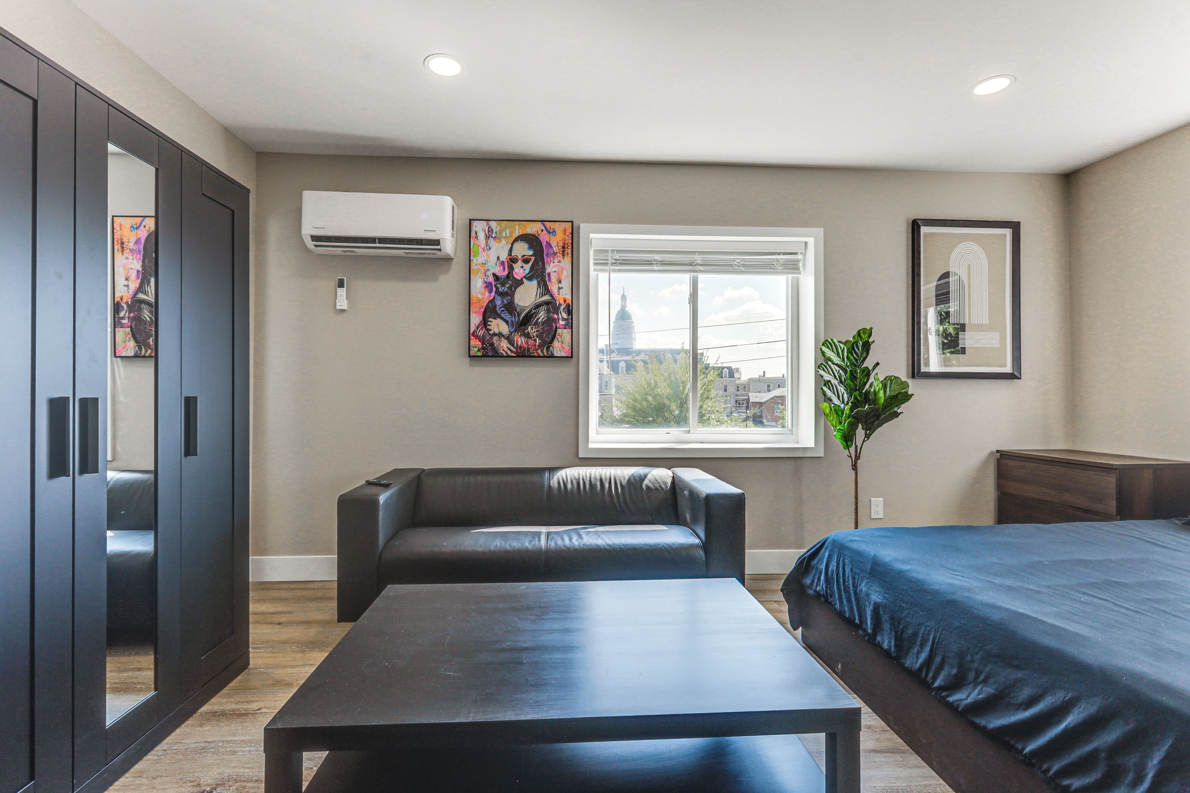 Een moderne hotelkamer met een bed, een bank, een tafel en kunstwerken aan de muur.