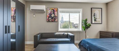 A modern hotel room with a bed, a sofa, a table, and artwork on the walls.