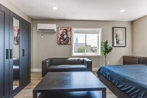 Een moderne hotelkamer met een bed, een bank, een tafel en kunstwerken aan de muur.