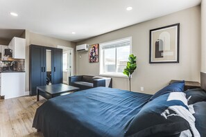 Ein modernes Schlafzimmer mit einem großen Bett, einer Sitzecke und einer Küchenzeile.