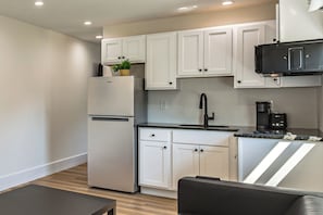 A modern kitchen with white cabinets, a stainless steel refrigerator, a coffee maker, and a black microwave.