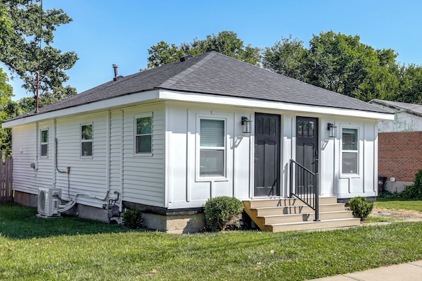 A single-story residential house with a front porch, a chimney, and a small front yard.