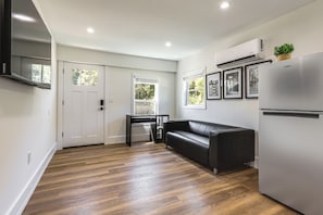 A modern kitchen with a black leather sofa, a built-in refrigerator, and a dining table. - Modern Retreat w/ Deck & Workspace Unit A (Cincinnati)