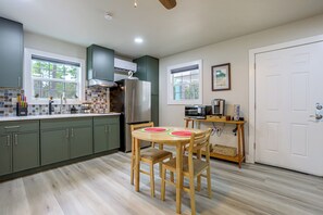 Une cuisine moderne avec un coin repas, comprenant un réfrigérateur, un four à micro-ondes et une table en bois avec des chaises.