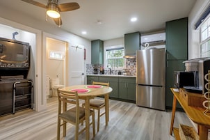 Una cocina moderna con un refrigerador de acero inoxidable, un microondas y un horno empotrado. Hay una mesa de comedor con sillas y un ventilador de techo.