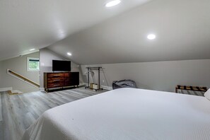 Une chambre à coucher avec un lit, une commode, un téléviseur et un ventilateur de plafond.