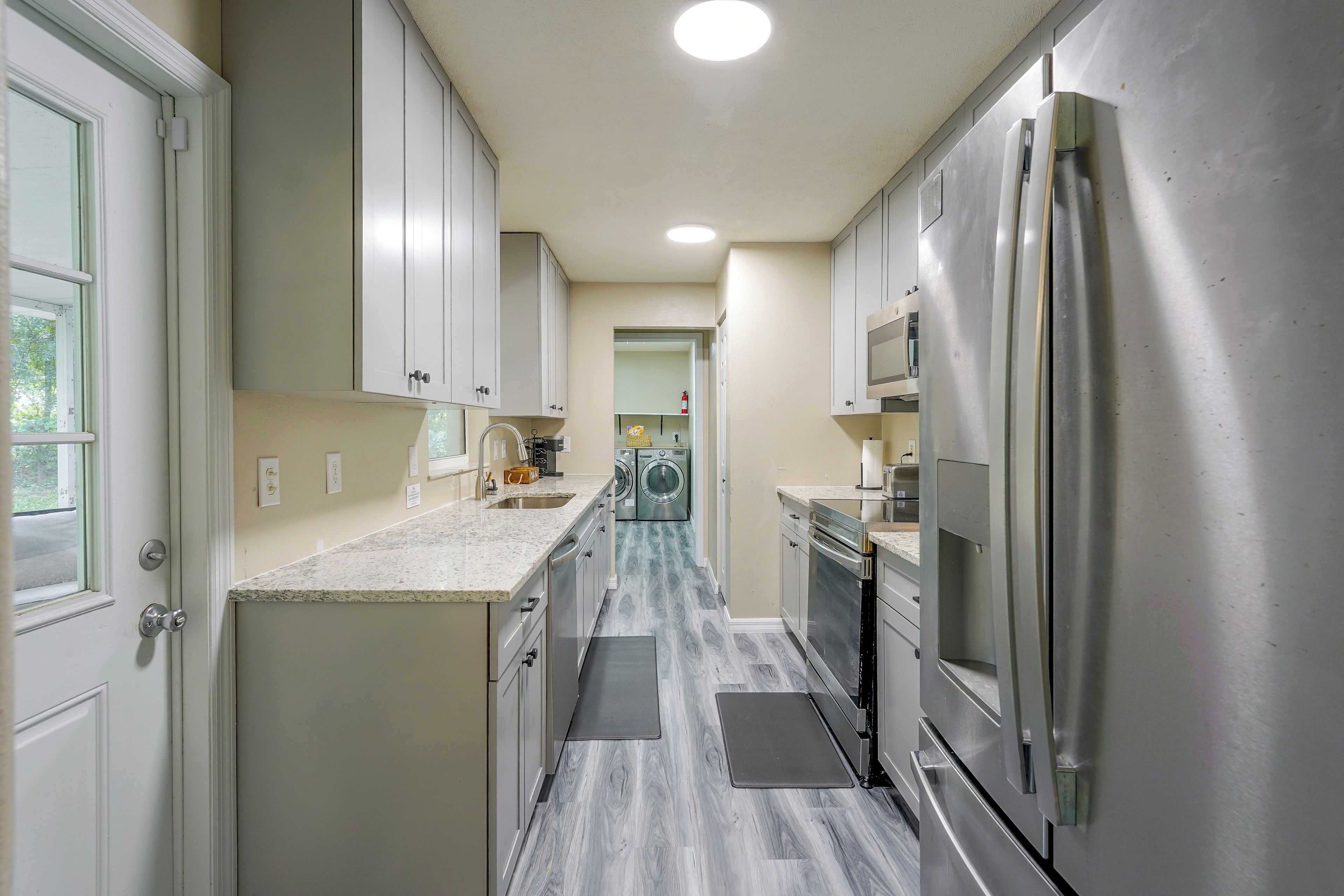 A modern kitchen with stainless steel appliances, white cabinetry, and a marble countertop.