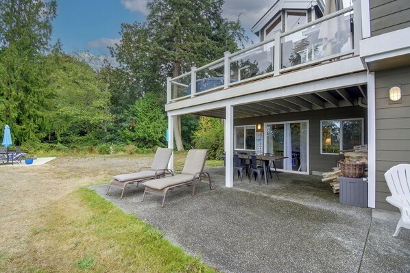 A two-story building with a covered patio area featuring outdoor seating and a table. - Puget Sound Views & Patio: Point No Point Apt (Hansville)