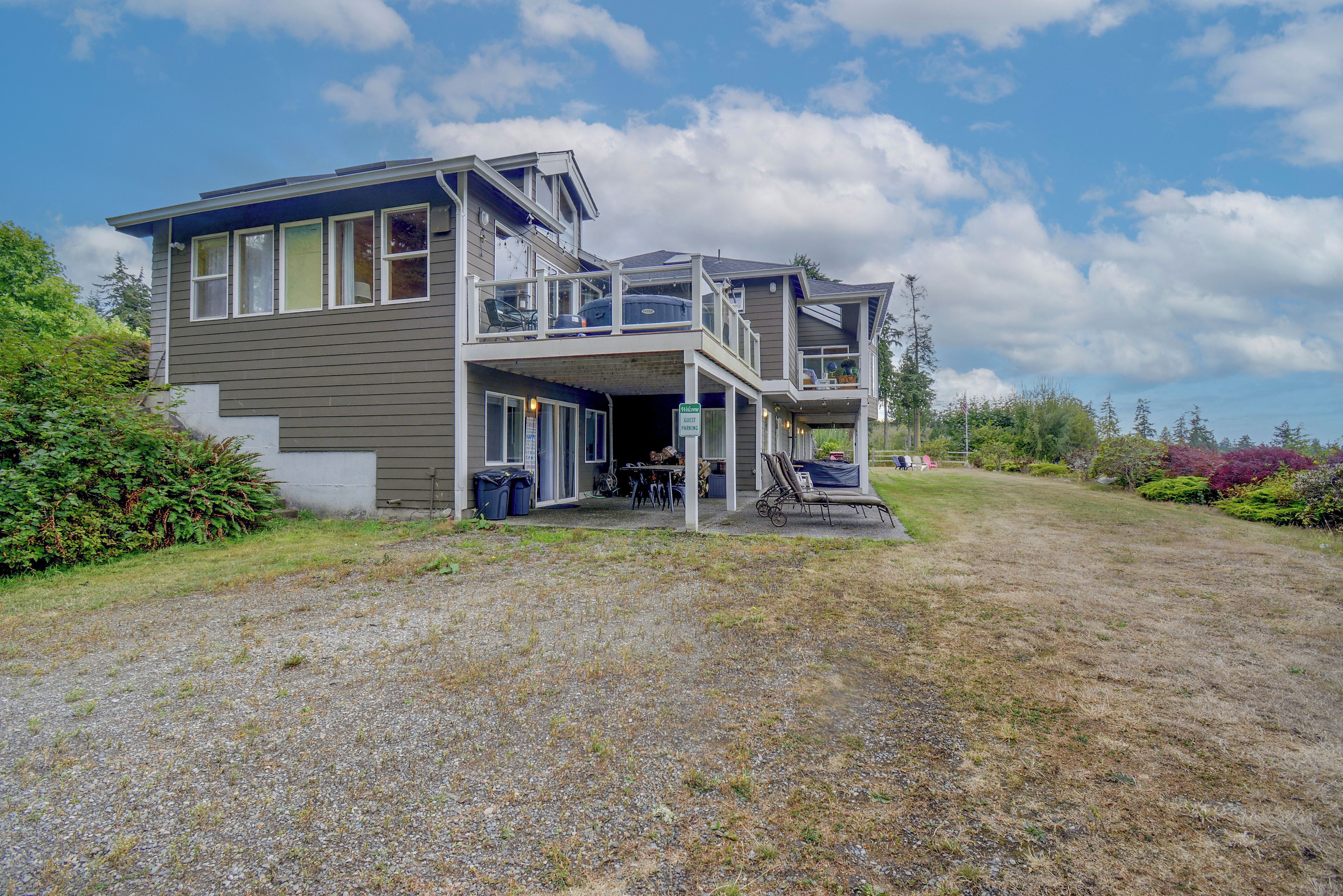 A two-story house with a balcony, a covered porch, and a gravel driveway.