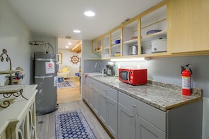 A kitchen with grey cabinets, a red microwave, and a fire extinguisher.