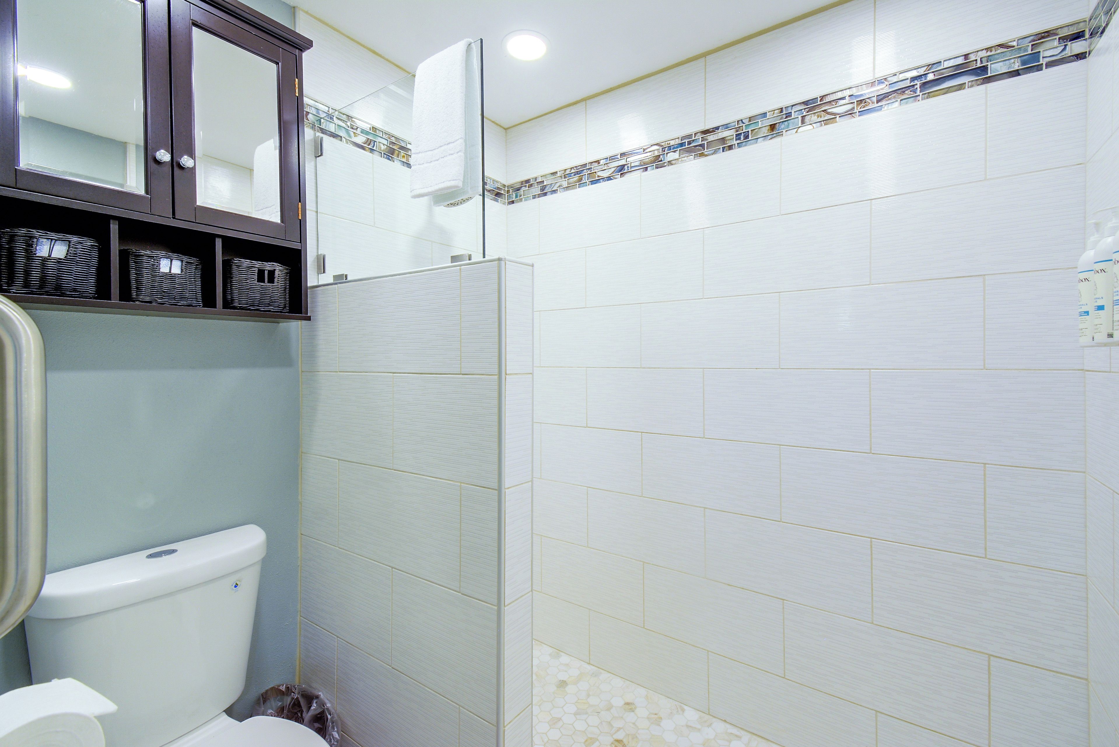Un bagno con il water, uno stendimento doccia e uno specchio sopra il lavandino.