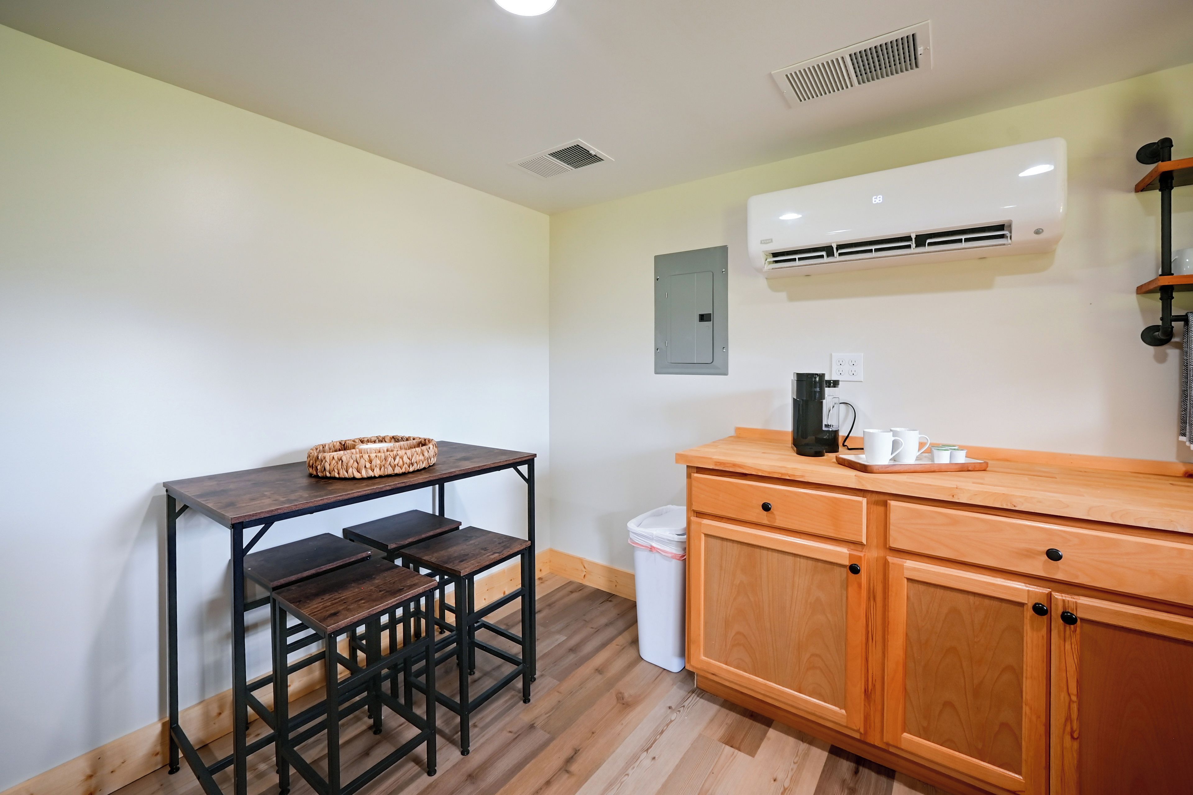 Una cocina compacta con una mesa de madera, una cafetera y un bote de basura.