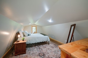 Une chambre à coucher avec un lit, une table de chevet, une lampe, une fenêtre et un miroir.