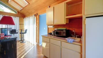 A compact kitchen with wooden cabinets, a microwave, and a sink.