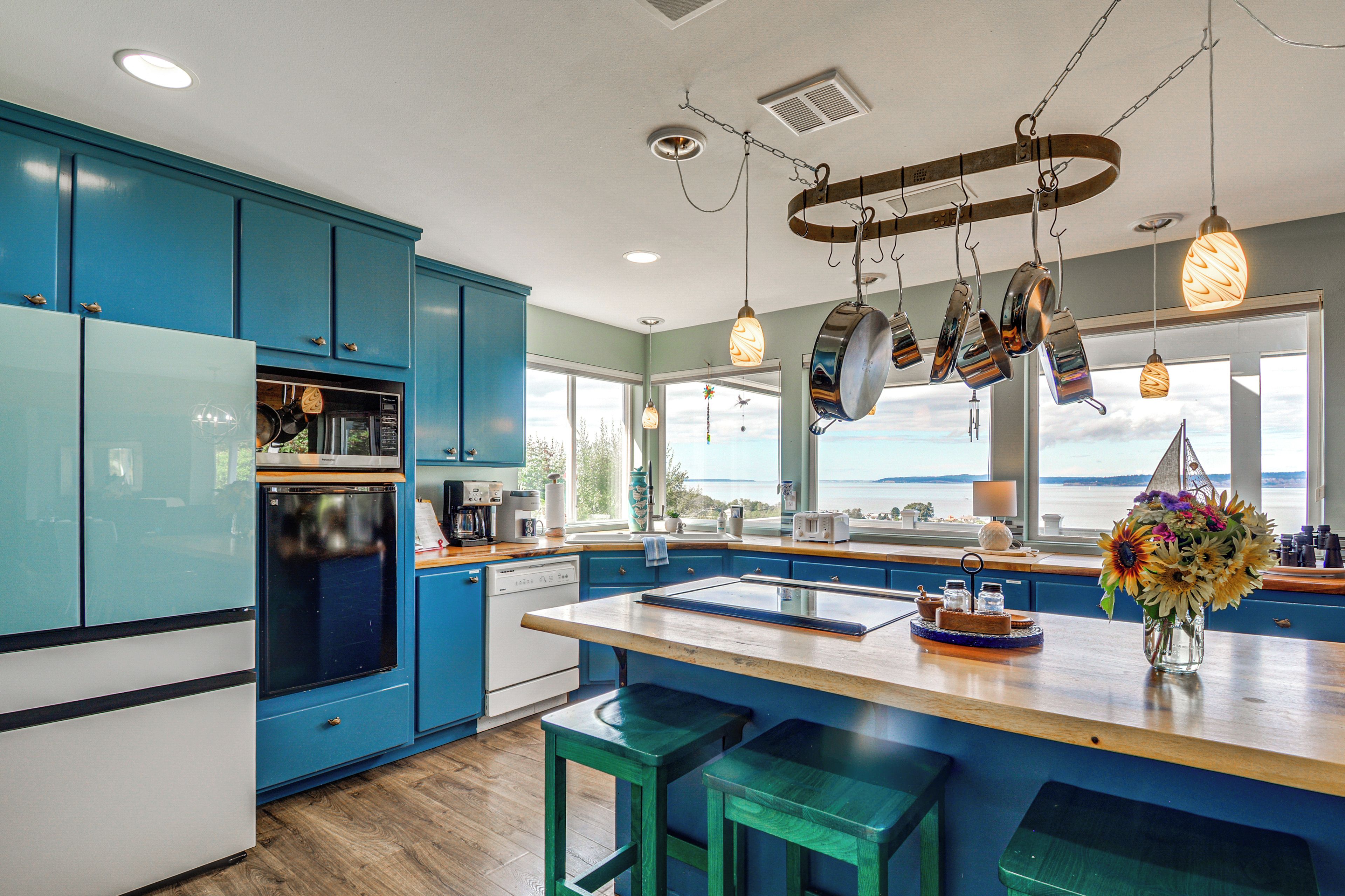 A modern kitchen with blue cabinets, stainless steel appliances, and a large island with bar stools.
