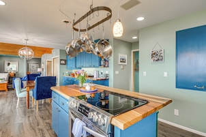 Una cocina moderna con armarios azules, encimera de madera y electrodomésticos de acero inoxidable.