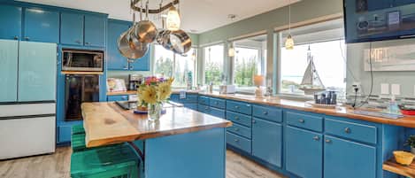 Una cocina con armarios azules, una isla de madera y utensilios de cocina de acero inoxidable colgados en la parte superior.
