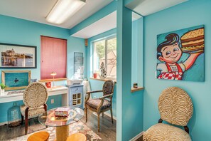 A room with teal walls, a desk with a computer, chairs, a window with blinds, and a painting of a burger. - Sound-view Deck! Retreat Near Point No Point Light (Hansville)