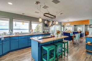 A modern kitchen with blue cabinets, a wooden island, and a view of the water. - Sound-view Deck! Retreat Near Point No Point Light (Hansville)