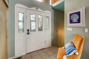 A closed white door with a window, a framed picture on the wall, and a brown chair with a striped pillow. - Sound-view Deck! Retreat Near Point No Point Light (Hansville)