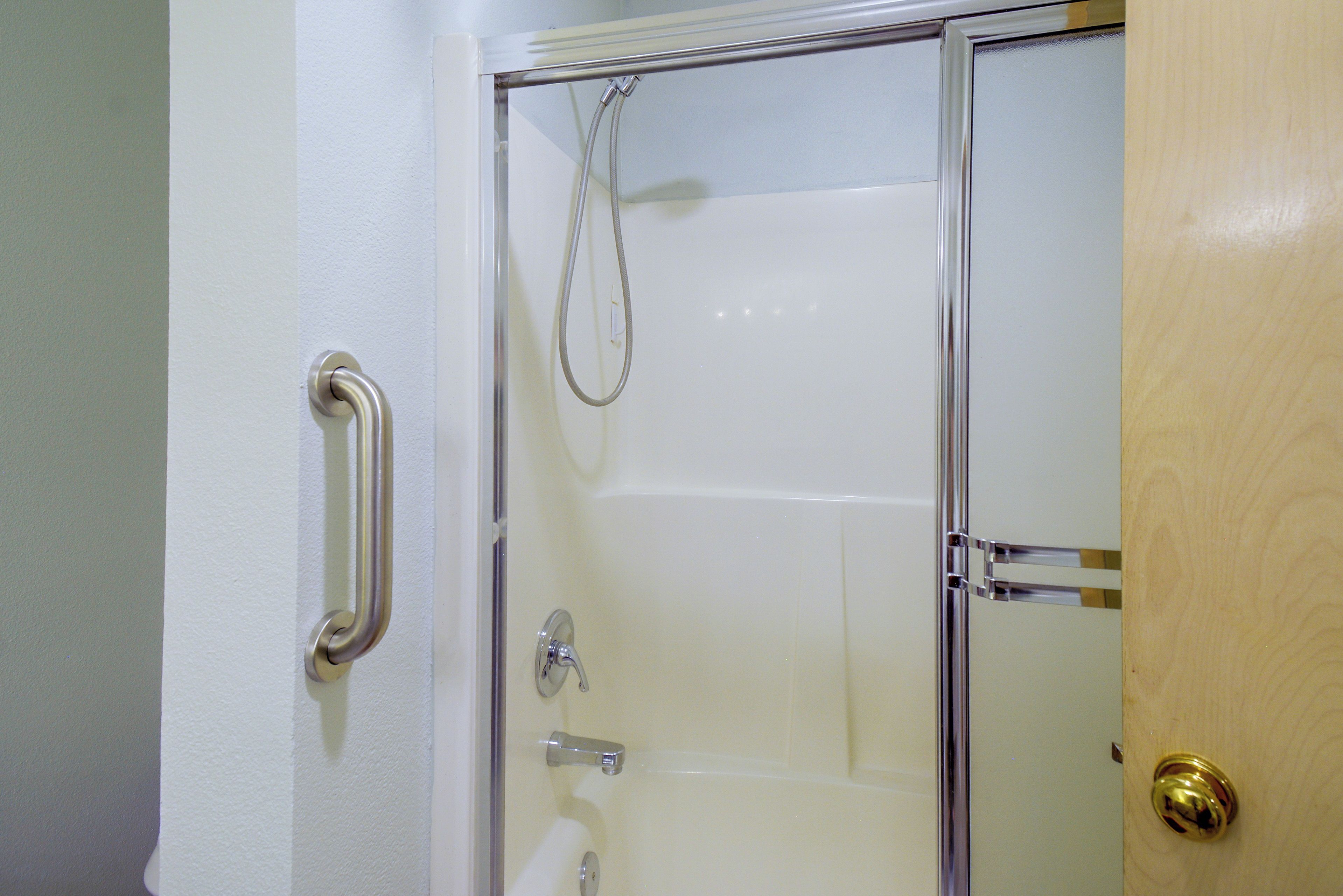 Een badkamer met een douchecabine van glas, een witte deur en een gouden deurklink.