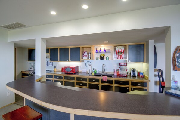Una cocina moderna con una isla curvada, armarios empotrados y diversos electrodomésticos.