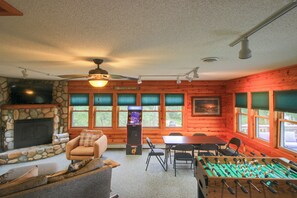 Ein gemütliches Blockhaus-Interieur mit Kamin, Kicker, Spielkonsole und Essbereich.