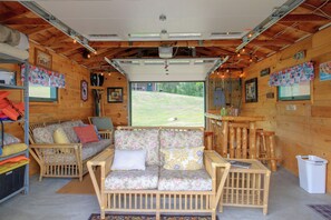 Ein gemütliches Interieur mit einer Sofagarnitur, Holzwänden und Blick ins Freie.