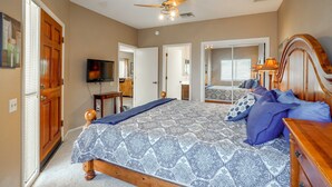 A bedroom with a bed, a ceiling fan, a television, and a bathroom visible through an open door. - Desert-view Green Valley Retreat Near Golf Courses (Green Valley)