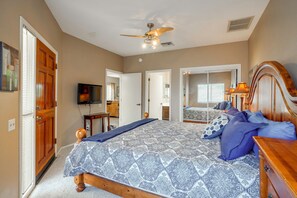 A bedroom with a bed, a ceiling fan, a television, and a bathroom visible through an open door. - Desert-view Green Valley Retreat Near Golf Courses (Green Valley)