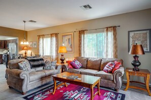 A living room with a sofa set, a coffee table, and a lamp. There is a kitchen in the background. - Desert-view Green Valley Retreat Near Golf Courses (Green Valley)