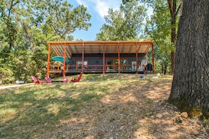 Une cabane dotée d’une terrasse couverte et d’un espace salon extérieur.