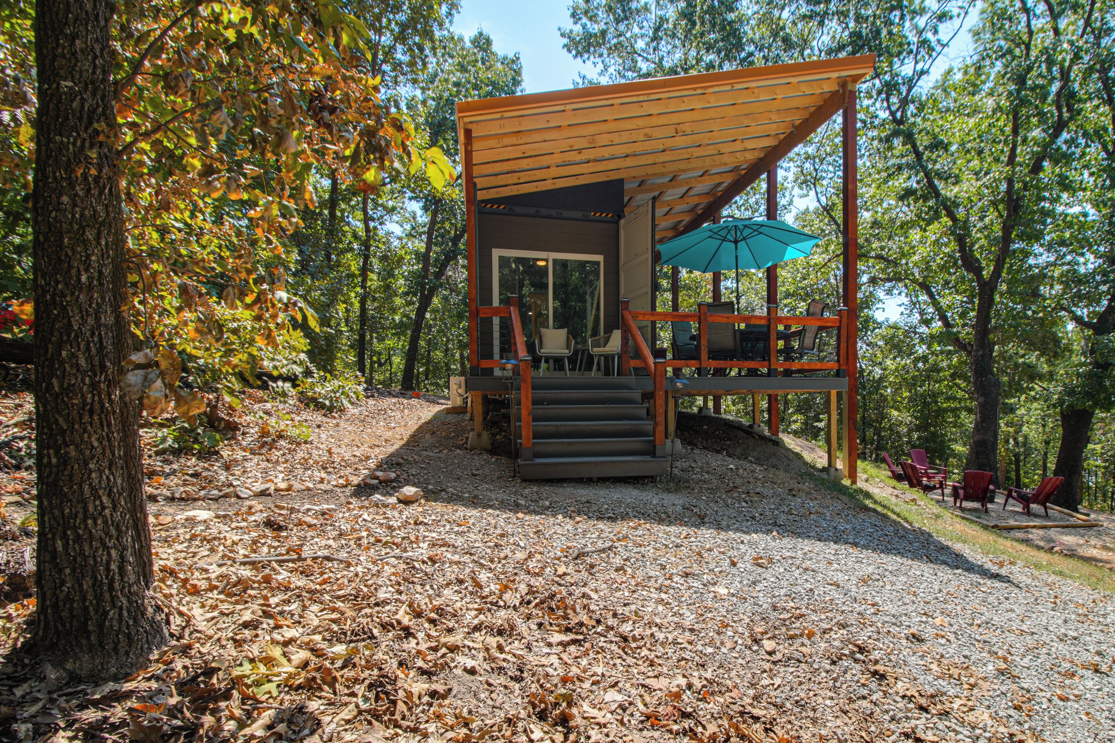A wooden cabin with a porch, outdoor seating, and a gravel path.