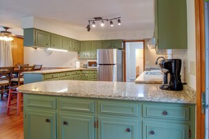 Una cocina con gabinetes verdes, un refrigerador de acero inoxidable y una encimera de granito.