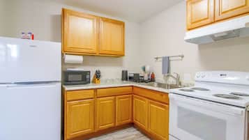 A kitchen with wooden cabinets, a refrigerator, a microwave, a stove, and a sink.