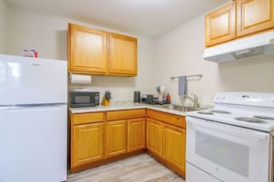 A kitchen with wooden cabinets, a refrigerator, a microwave, a stove, and a sink.