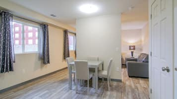 A room with a dining table, chairs, a sofa, and a lamp.