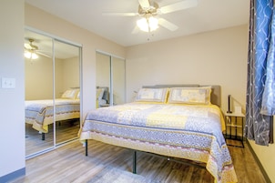 A bedroom with a bed, a ceiling fan, a mirror, and a nightstand.