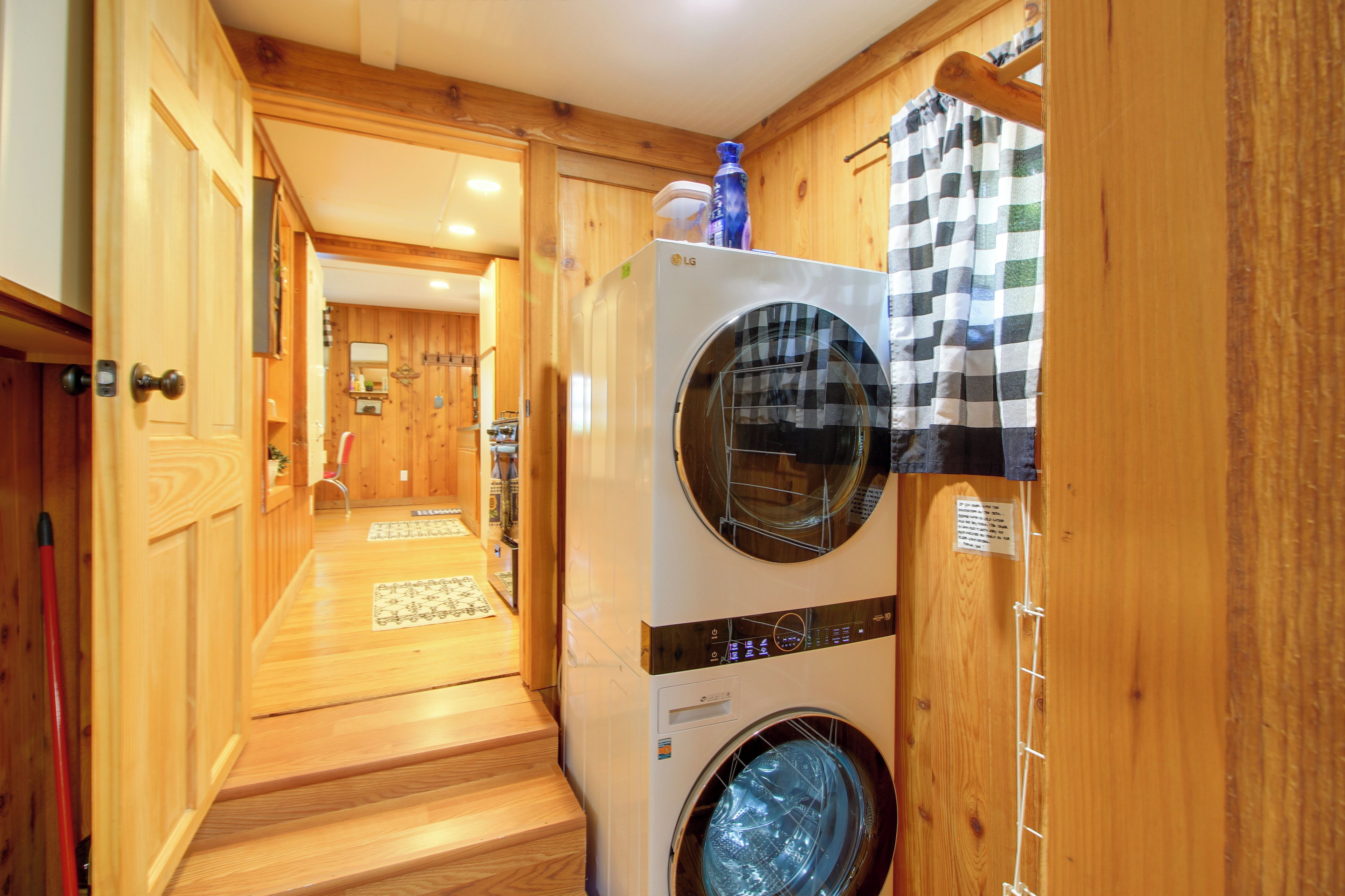 A laundry area with a washing machine and dryer, wooden walls, and a checkered towel hanging on the dryer door.