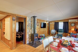 A cozy room with a stone wall, wooden furniture, a fireplace, and a dining area set for a meal. - Sibley Shores Waterfront Cabin w/ Dock & 28 Acres (Pequot Lakes)