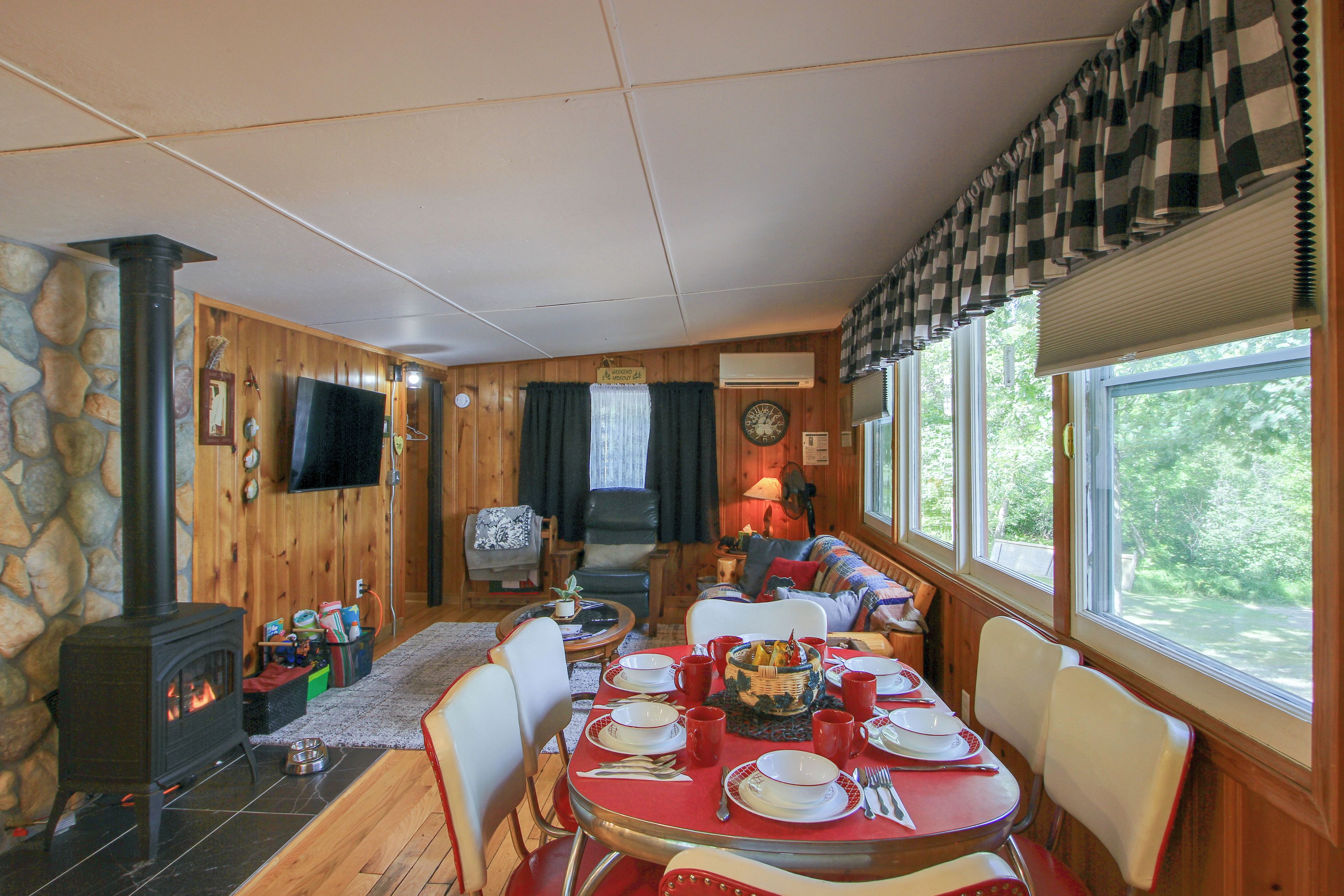 A cozy cabin interior with a dining table set for four, a fireplace, and a television mounted on the wall.