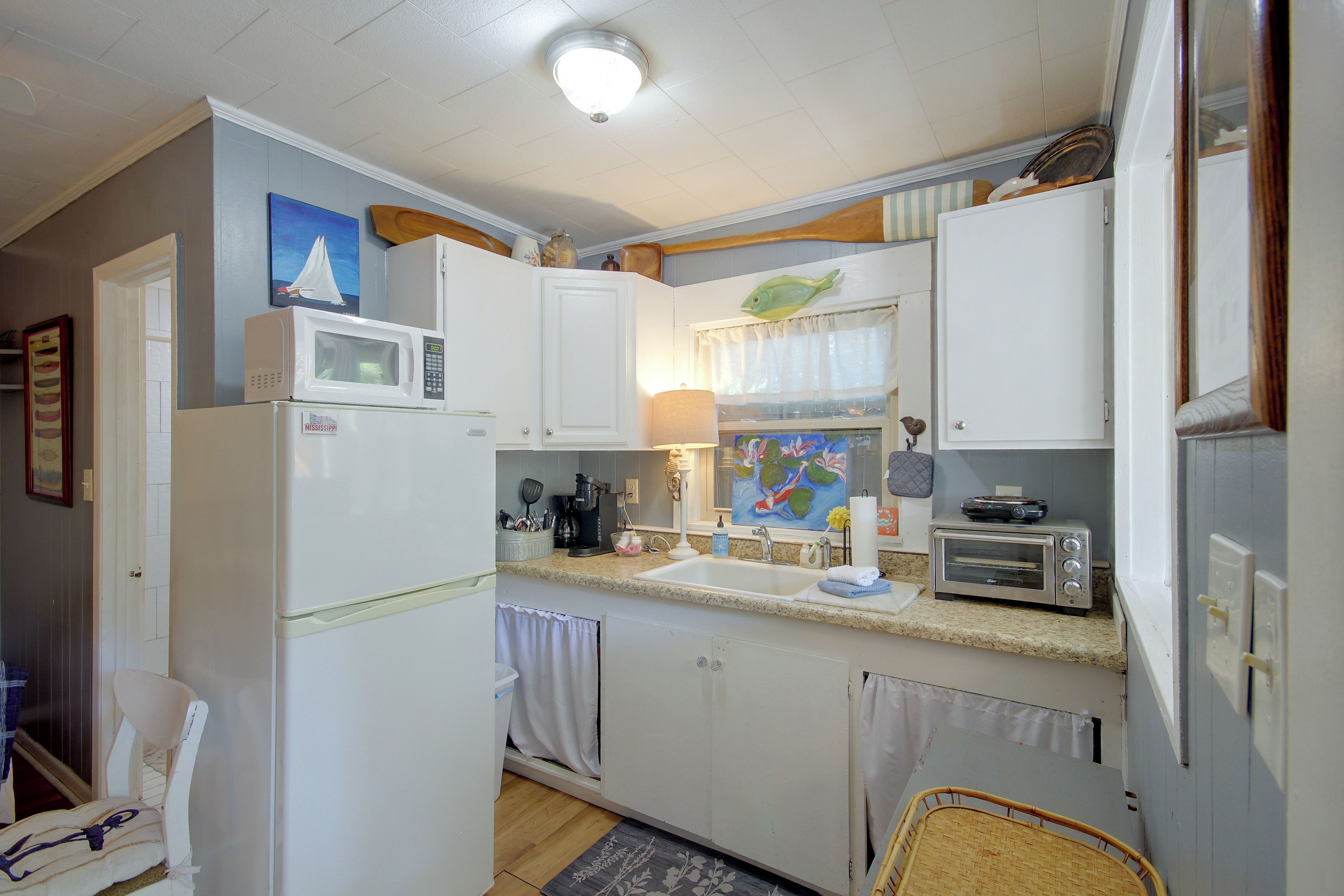 A compact kitchen with white appliances, a sink, and a toaster.