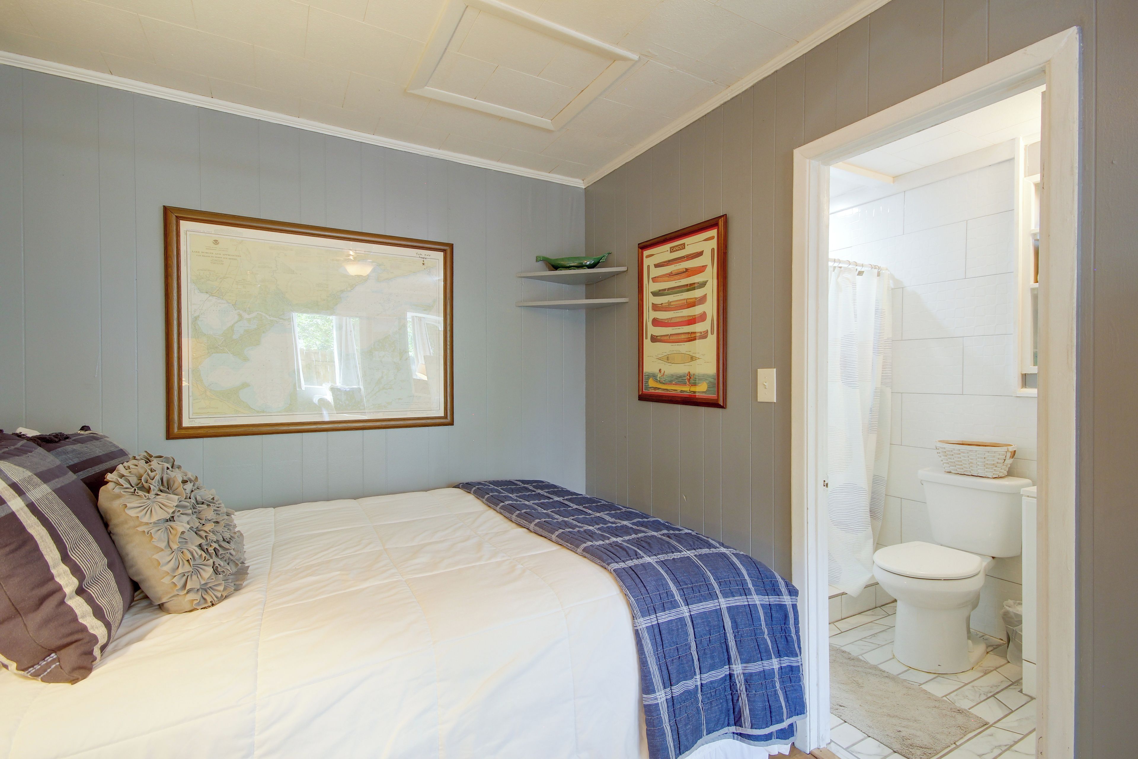 Une chambre à coucher avec un lit, une carte et une affiche représentant un canoë accrochée au mur.