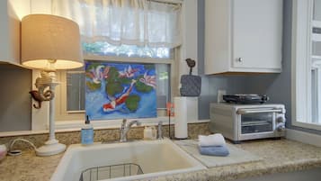 A kitchen with a sink, a toaster, a painting, a lamp, and a decorative seahorse.