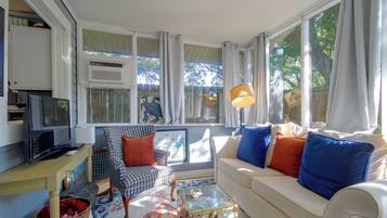 Una sala de estar con sofá, sillón, televisión y una ventana con cortinas.