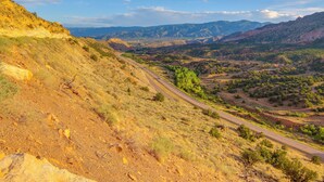 A winding road through a hilly landscape with sparse vegetation and distant mountains. - See the Royal Gorge! Cañon City Apartment (Canon City)