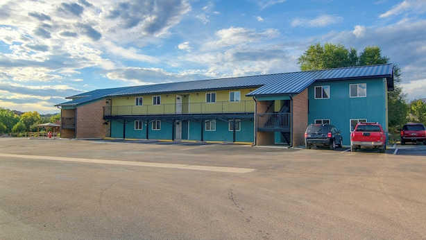 A multi-story building with a blue roof and a parking lot in front. - See the Royal Gorge! Cañon City Apartment (Canon City)