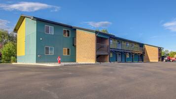 A multi-story building with a flat roof, a fire hydrant, and a parking lot.