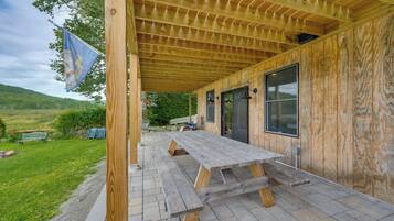 A wooden deck with a picnic table, a flag, and a view of a green landscape.