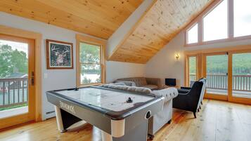 A spacious room with a pool table, a sofa, and a large window offering a view of the outdoors.
